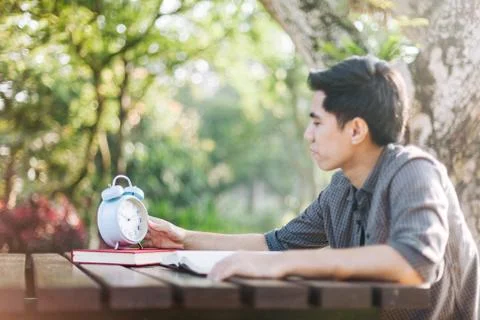 Focus on clock, Young man looking at clock while studying Stock Photos