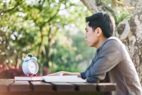 Focus on clock, Young man looking at clock while studying Stock Photos