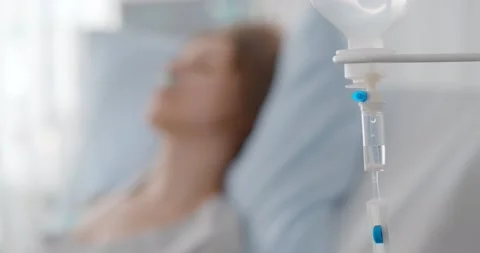 Focus on dripper with medication and sick woman resting in hospital bed on Stock Footage 148985026