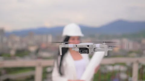 Focus on drone flying and hovering in air, against background of woman in helmet Stock Footage 240341936