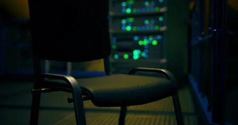 Focus on an empty chair in a dimly lit server room filled with lights Stock Footage 308674306
