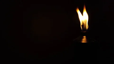 Focus on a flaming torch in the dark. 
The camera suddenly pans and reveals a Stock Footage 120040976