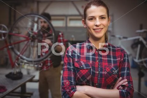 Focus On Foreground Of Woman Mechanic With Arms Crossed