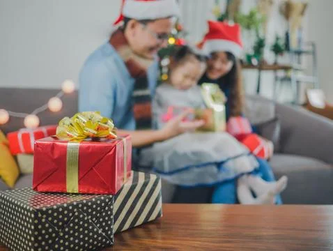 Focus gift box and blurred background asian young family on Christmas exchang Stock Photos