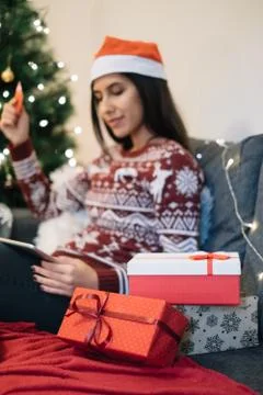 In focus gift boxes and blurred woman holding tablet and card Foto stock