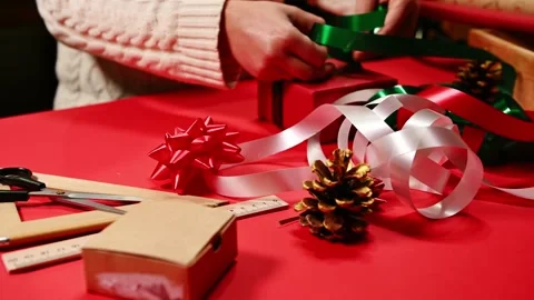 Focus on golden pine cones on blurred background of a woman wrapping a Christmas Stock Footage 221020439