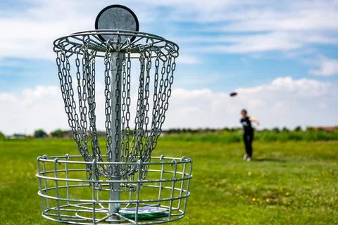Focus on a golf hole while disc is in the air after being tossed by a defocused Foto stock