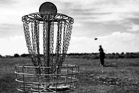 Focus on a golf hole while disc is in the air after being tossed by a defocused Foto stock