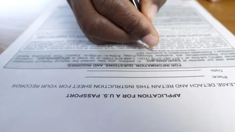 Focus on hand of young black man filling out passport application form for US Stock Footage 240321649