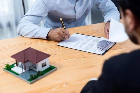 Focus house sample house model with blurred satisfied signing contract. Fervent Stock Photos