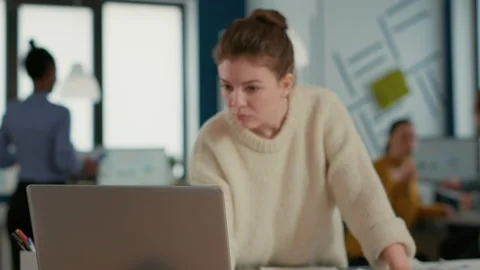 Focus on laptop in front of startup employee looking and charts comparing sales Stock Footage 219585261