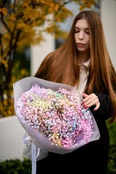 Focus on a large bouquet of multi-colored gypsophila in the hands of a pretty Stock Photos