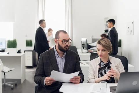 Focus on man with documents in his hands talking with woman sitting at a table Stock Photos