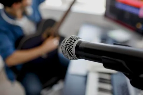 Focus on the microphone, blurred background Man plays guitar and produce elec Stock Photos