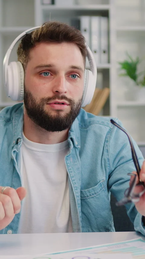 Focus on mobile phone camera from which good-looking confident in headphones adu Stock Footage 333852971