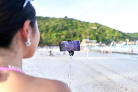 Focus on a mobile in a selfie stick held by a streamer on a beach Stock Photos