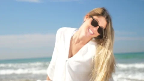 Focus in on a model sitting smiling at the beach Stock Footage 83848464