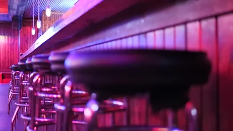 Focus pull along empty bar stools under purple lights. Stock Footage 161652750