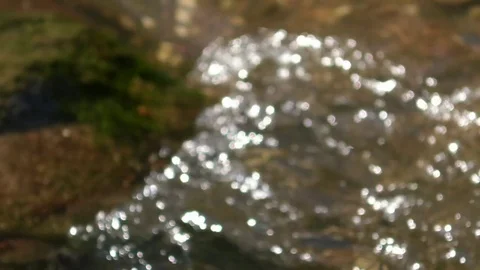 Focus pull: Dancing, sparkling spots of light turn into swirling, flowing water Video stock 76766473