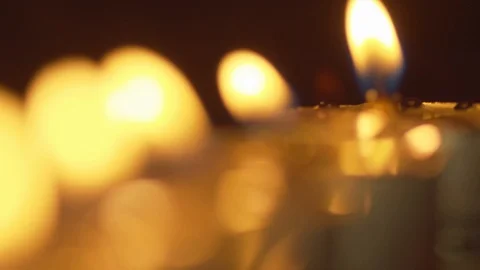 Focus pull from far to near along a line of candles with their golden Stock Footage 123390036