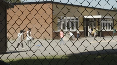 Focus pull from fence to children playing on the school yard. Static shot. Stock Footage 112942587