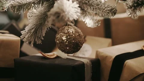 Focus pull from a gift under a Christmas tree to a single shiny gold Stock Footage 226142441