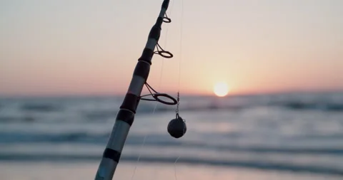 Focus pull from ocean waves to fishing pole during sunset (100fps) Stock Footage 130380147