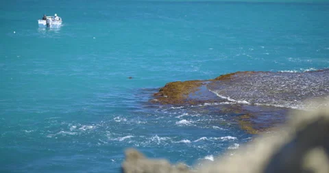 Focus pull from rock to seaweed. Boat with recreational fishermen Stock-Footage 140894588