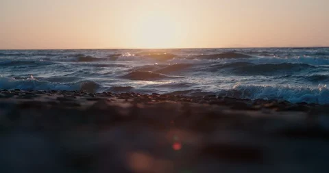 Focus pull from sandy beach and pebbles to ocean during sunset Stock Footage 129826638