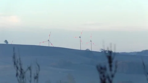 Focus Pull: Wind turbines behind a hill, farmland, withering agricultural plants Stock Footage 97750169