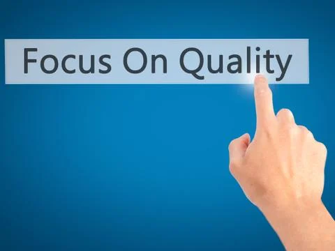 Focus On Quality - Hand pressing a button on blurred background concept on vi Foto stock