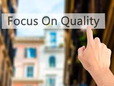 Focus On Quality - Hand pressing a button on blurred background concept on vi Stockfoto's
