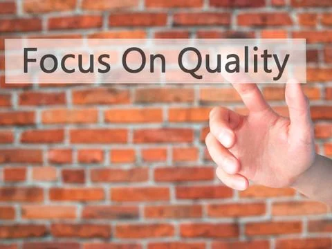 Focus On Quality - Hand pressing a button on blurred background concept on vi Stockfoto's