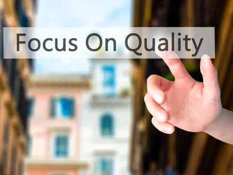 Focus On Quality - Hand pressing a button on blurred background concept on vi Stock Photos