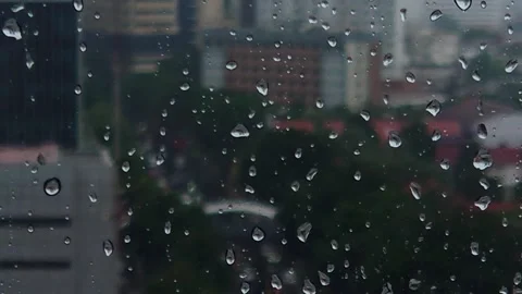 Focus on raindrops dripping on the window against the backdrop of a busy city Stock Footage 288547821