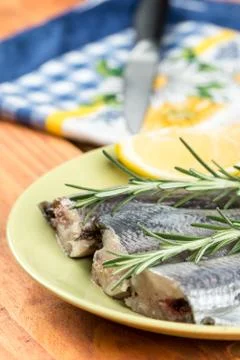 Focus on raw hake fish on the plate with rosemary and lemon Stock Photos
