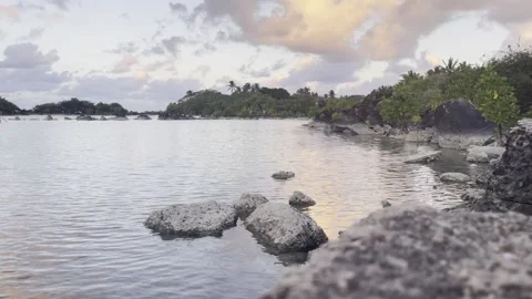 Focus on rocks in a rockpool at sunset with wind blowing 스톡 동영상 275333973