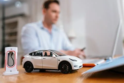 Focus scale EV car and charging station mockup model. Synchronos Stock Photos