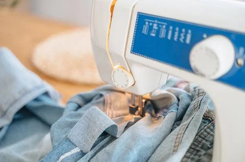 Focus on sewing machine foot stitching denim with soft warm built-in light,.. Stock Photos