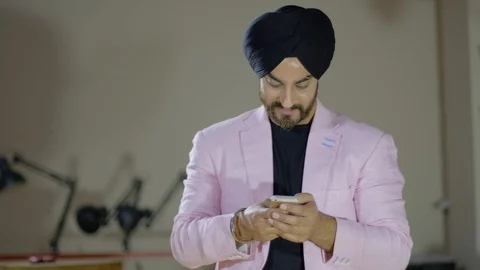 Focus shift and tilt down from a Sikh business executive busy with a smart phone Stock Footage 102419982