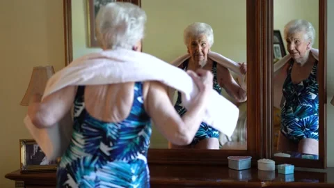Focus shift from back of elderly woman to front, wearing swimsuit and beach Video stock 140743439