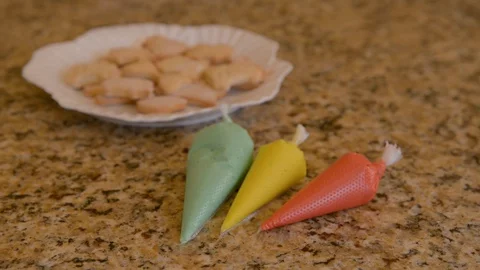 Focus shift from multi-colored creams in packets to plate with cookies, close-up Stock Footage 127629764