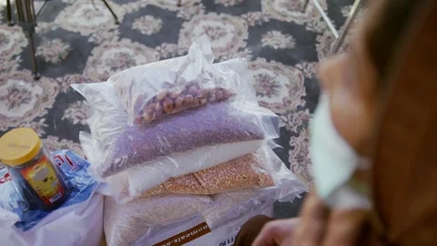 Focus shifts from basic meal packets to the lady in mask. 库存影片 167234378