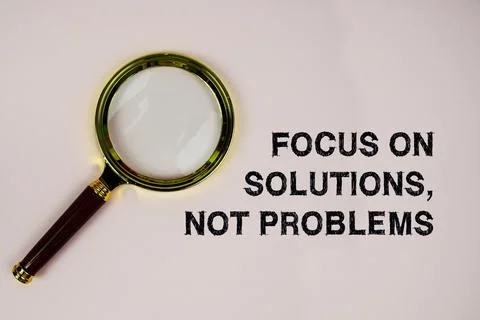 Focus On Solutions, Not Problems text with magnifying glass on pink backgroun Stock Photos