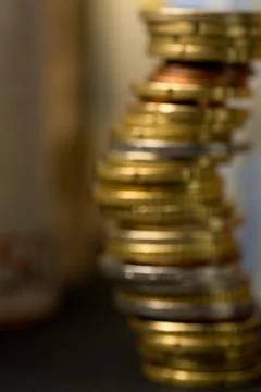 Of focus stack of euro coins and rolls of bank notes in the background Stock Photos