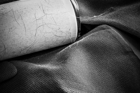 Focus stack of a lint roller resting on a dark suit jacket to remove pet animal Stock Photos