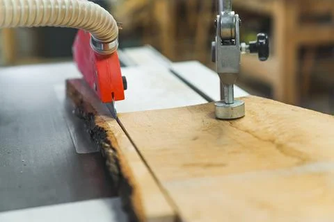 Focus on table saw blade cutting wooden plank. Woodworking workshop interior and Stock Photos