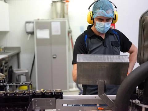 Focus on a worker using a machine in the beer canning production line Stock Photos