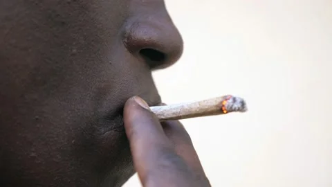 Focus on young addicted black man man putting cigarette to mouth Stock Footage 231679747