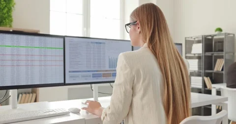 Focused accountant analyzing finance spreadsheets on multiple computer monitors Stock Footage 344802648